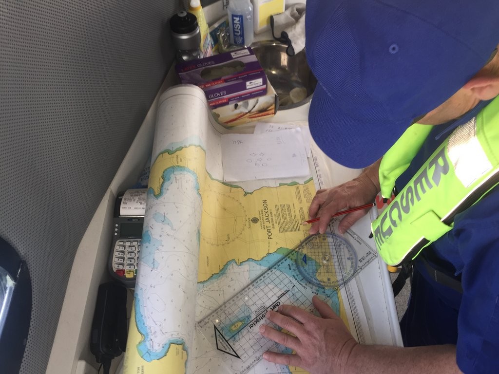 Crew member fixing position on paper chart.